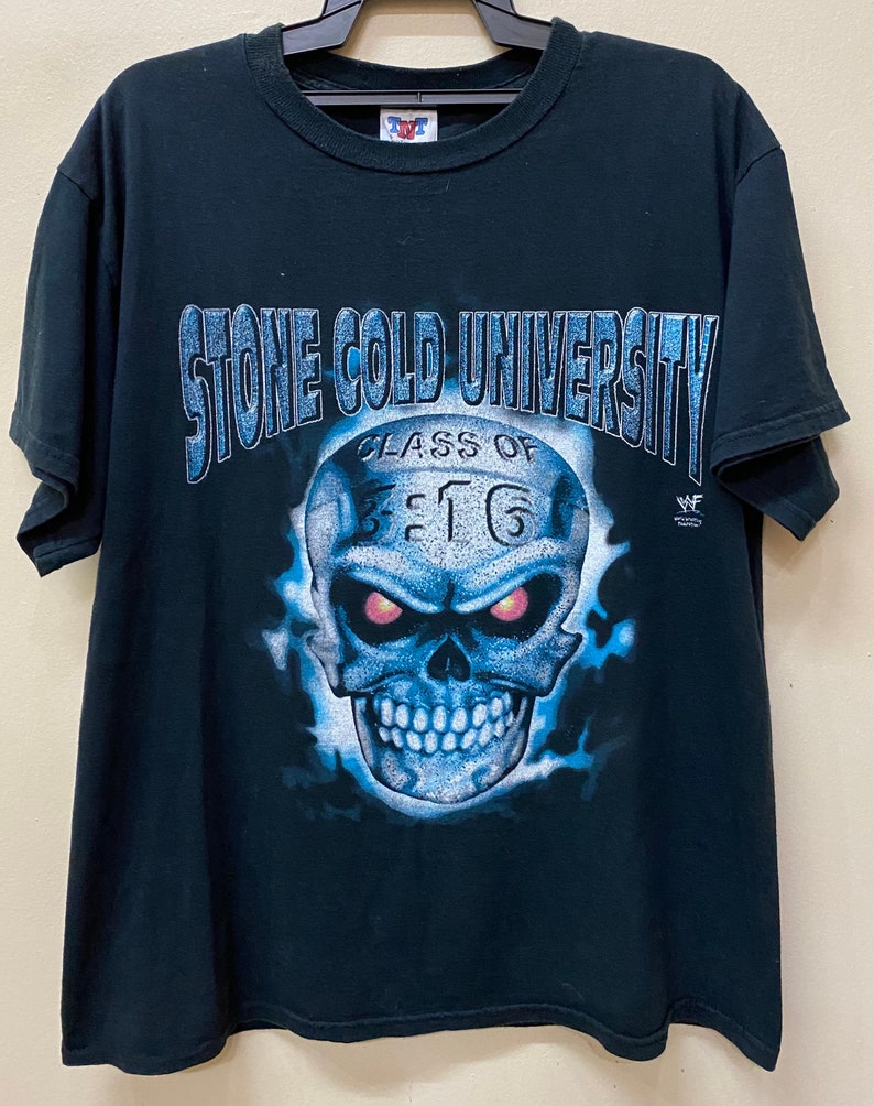 May include: Black t-shirt with a blue and white skull graphic. The skull has red eyes and the text "Stone Cold University Class of 3:16" above it. The WWF logo is in the bottom right corner.