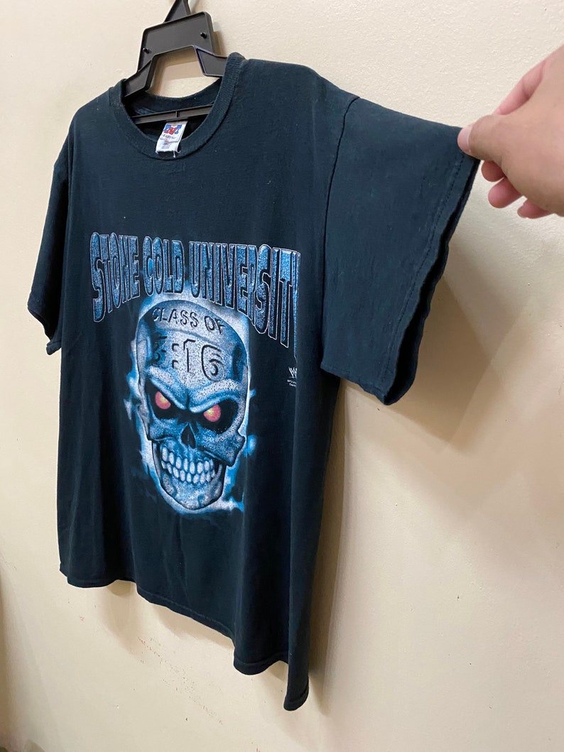 May include: Black t-shirt with a blue and white skull graphic. The skull has red eyes and the text "Stone Cold University Class of 3:16" is printed on the shirt.