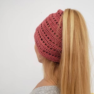 May include: A crocheted beanie hat in a dusty rose colour with a hole in the back for a ponytail.