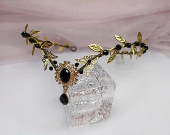 May include: A gold leaf and black bead headband with a large black gemstone pendant. The headband is on a white surface.