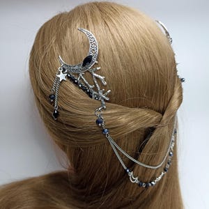 May include: Silver hair comb with a crescent moon design, black beads, and a dangling chain with stars and moons.