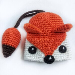 May include: A crocheted fox toy with a white body, orange head and tail, and black eyes and nose.