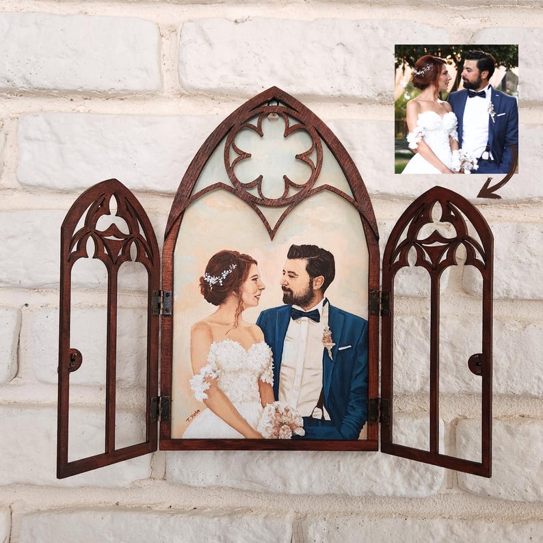 May include: A wooden frame with three arched windows, each with intricate carvings. The center window displays a painted portrait of a couple in wedding attire, while the side windows are open. The frame is mounted on a white brick wall.
