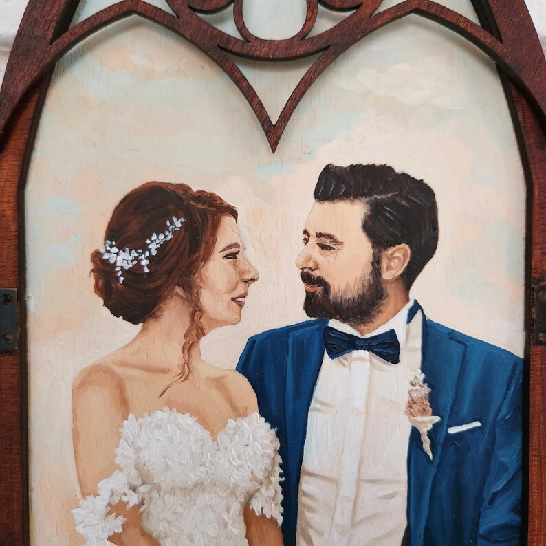 May include: A painting of a bride and groom in a wedding portrait. The bride is wearing a white dress with lace detailing and a floral crown. The groom is wearing a blue suit with a white shirt and a bow tie. They are looking at each other with smiles on their faces.