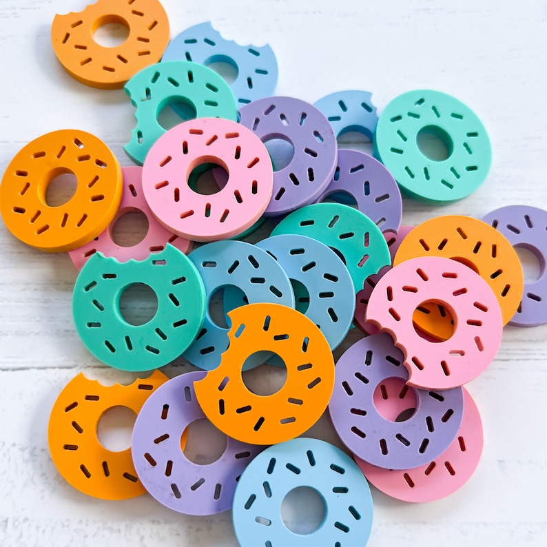 Op de afbeelding: Een verzameling kleurrijke donutvormige siliconen mallen in verschillende kleuren, waaronder turquoise, paars, roze, blauw en oranje.