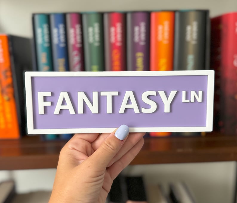 Peut inclure: Une pancarte violette avec une inscription blanche qui dit "FANTASY LN" avec une bordure blanche.