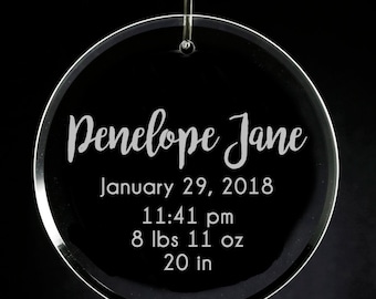 May include: A clear glass ornament with the text "Penelope Jane" engraved on it. The ornament also includes the date "January 29, 2018", the time "11:41 pm", the weight "8 lbs 11 oz", and the length "20 in".