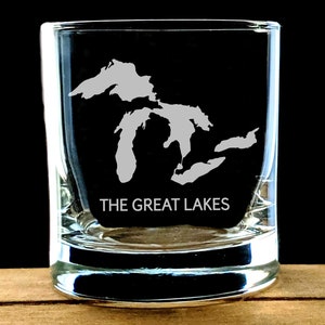 May include: A clear glass shot glass with an etched design of the Great Lakes and the text "THE GREAT LAKES".