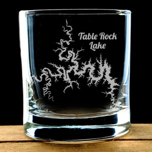 May include: A clear glass shot glass with an etched design of Table Rock Lake. The lake's outline is etched in white on the glass.