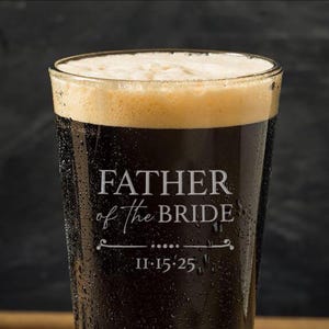 May include: A clear glass beer mug with the text "Father of the Bride" and the date "11.15.25" etched on the side. The mug is filled with dark beer.