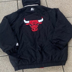 Könnte beinhalten: Schwarze Steppjacke mit einem roten und weißen Chicago Bulls Logo auf der Rückseite. Die Jacke hat eine Kapuze und einen Reißverschluss.