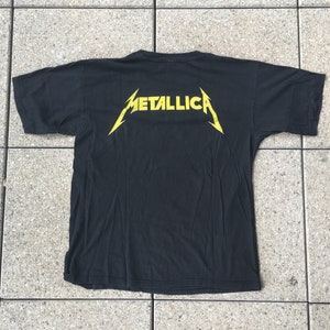 May include: Black t-shirt with a yellow "Metallica" logo on the back.