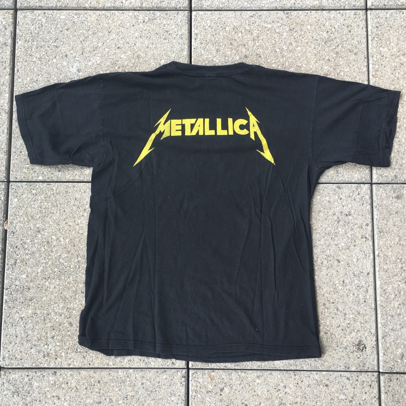 May include: Black t-shirt with a yellow "Metallica" logo on the back.
