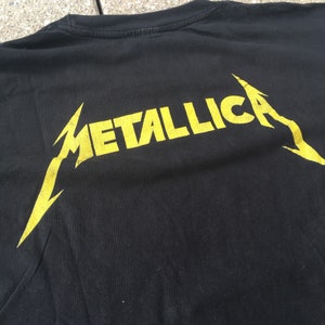 May include: Black t-shirt with a yellow Metallica logo on the back.