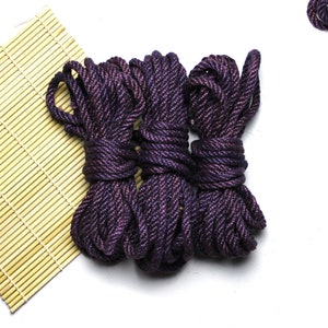 May include: Three spools of dark purple rope with a shimmery finish. The rope is coiled and tied together.