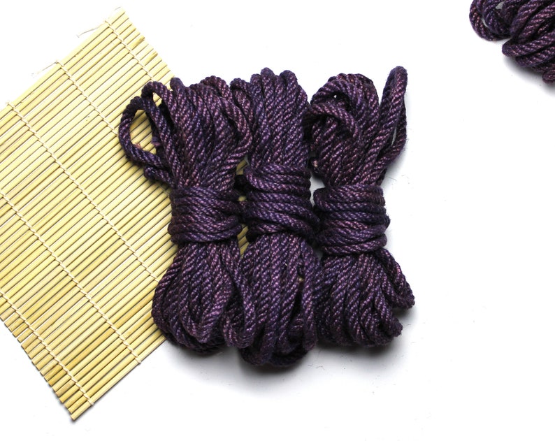May include: Three spools of dark purple rope with a shimmery finish. The rope is coiled and tied together.