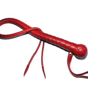 May include: A red leather whip with a braided handle and a knotted end. The whip has a strap attached to the handle.