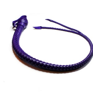 May include: A purple leather whip with a braided design. The whip is coiled in a circle and has a handle at one end.