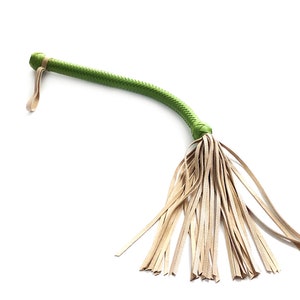 May include: A green leather whip with a tan leather fringe. The whip is made of braided leather and has a loop at the end.