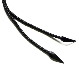 May include: Two black leather braided cords with pointed ends.