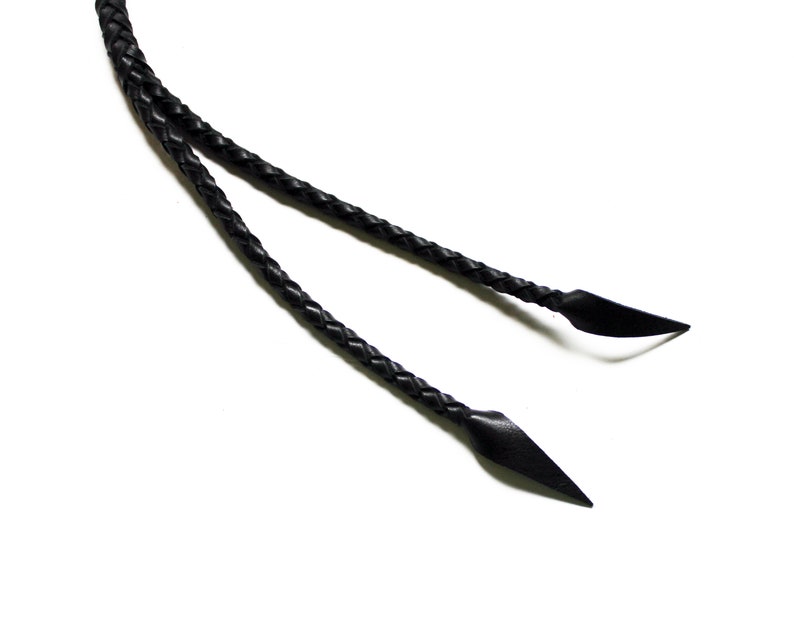 May include: Two black leather braided cords with pointed ends.