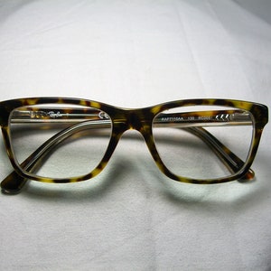 May include: Tortoise shell eyeglasses with a clear lens and the text "RAP7110AA 135 RC004" printed on the side.