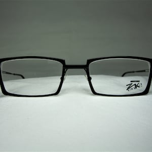 Peut inclure: Lunettes rectangulaires noires avec un logo Z enka sur la lentille droite.