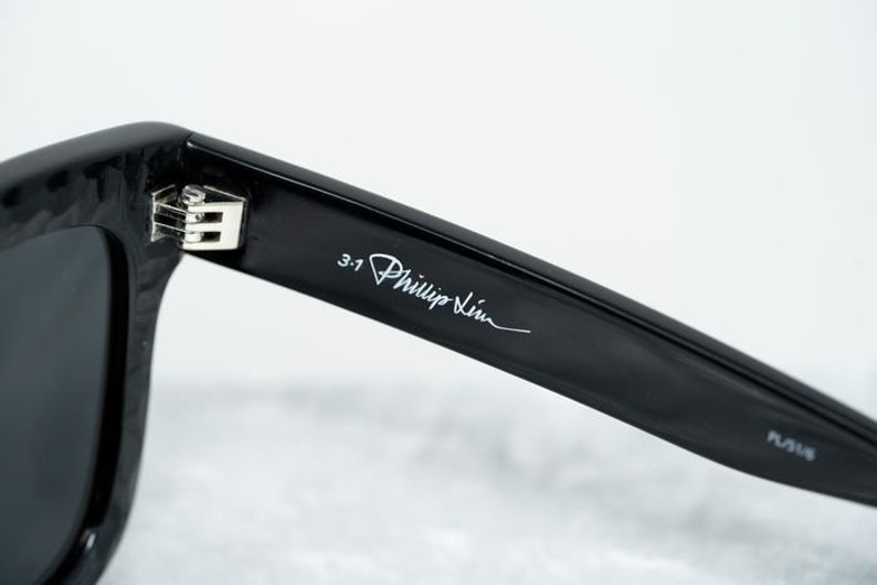 Puede incluir: Gafas de sol negras con el logotipo de 3.1 Phillip Lim en la varilla.