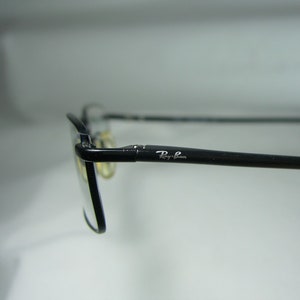 Puede incluir: Gafas Ray-Ban negras con un logotipo Ray-Ban plateado en el lateral.