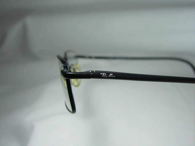 Puede incluir: Gafas Ray-Ban negras con un logotipo Ray-Ban plateado en el lateral.