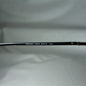 Puede incluir: Primer plano del brazo de unas gafas negras con el texto "RB6083 2509 50□16 135" impreso en el brazo.