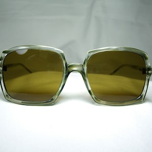 Może przedstawiać: Okulary przeciwsłoneczne vintage z przezroczystą oprawką w kolorze imitującym ż&oacute;łwiowy pancerz i brązowymi szkłami. Szkła mają kwadratowy kształt, a oprawka jest lekko zakrzywiona.