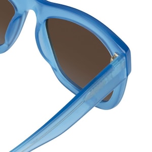 K&ouml;nnte beinhalten: Blaue get&ouml;nte Sonnenbrille mit einem dicken, abgerundeten Rahmen. Die Sonnenbrille hat dunkelbraune Gl&auml;ser.