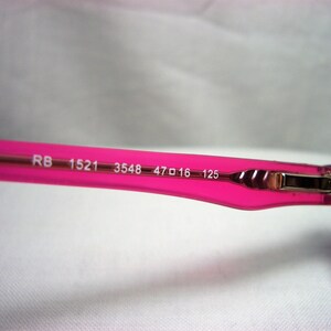 Puede incluir: Gafas de vista de color rosa y morado con el texto "RB 1521 3548 47□16 125" impreso en la montura.