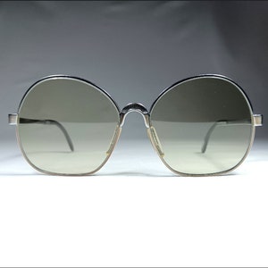 May include: Silver-framed round sunglasses with gray lenses.