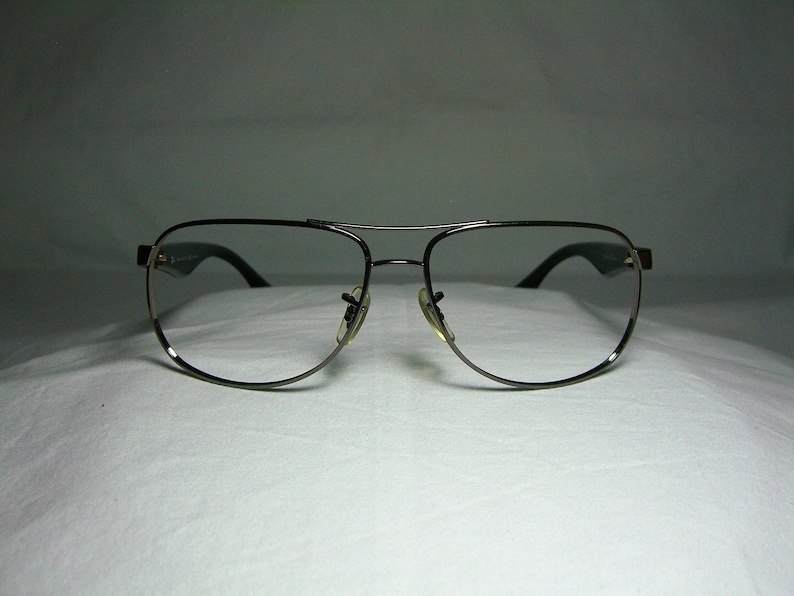 K&ouml;nnte beinhalten: Eine silberfarbene Aviator-Brille mit klaren Gl&auml;sern.