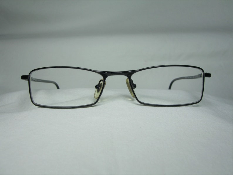 Puede incluir: Gafas rectangulares de metal negro con lentes transparentes.