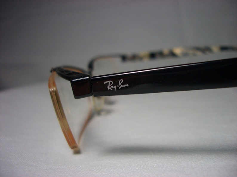 May include: Black Ray-Ban eyeglasses with a brown frame and clear lenses.