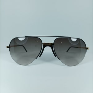 May include: Black aviator sunglasses with gold accents and brown gradient lenses.