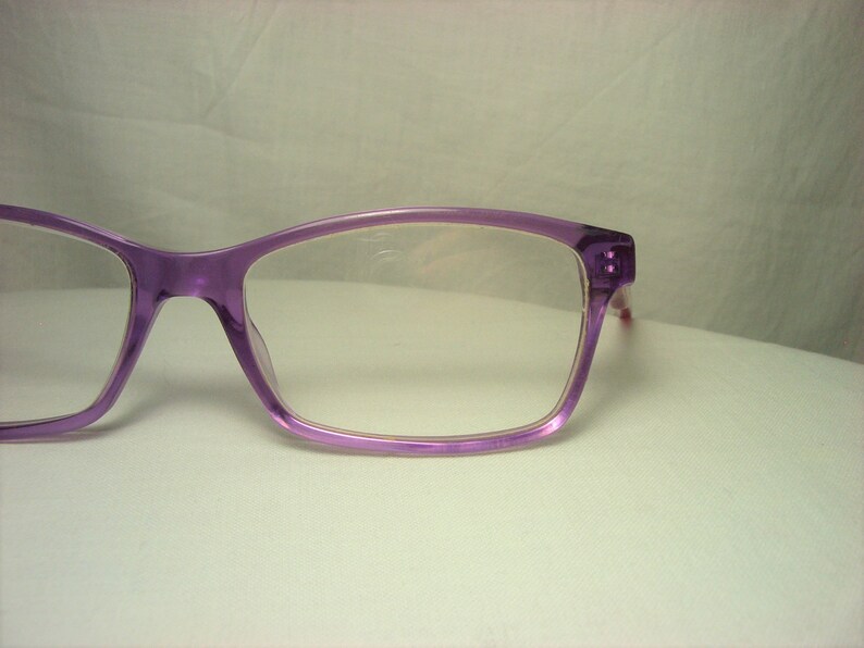 Puede incluir: Gafas de pl&aacute;stico de color morado con lentes transparentes.
