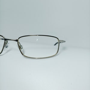 Puede incluir: Gafas rectangulares con montura plateada y lentes transparentes.