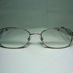 May include: A pair of brown metal eyeglasses with a rectangular frame and clear lenses.