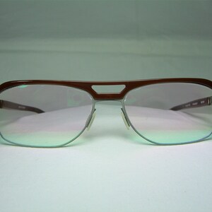 May include: Brown and silver aviator style eyeglasses with a light pink tint to the lenses.