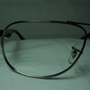 K&ouml;nnte beinhalten: Eine silberne Aviator-Brille mit klaren Gl&auml;sern. Die Brille hat einen d&uuml;nnen Metallrahmen und ist sowohl f&uuml;r M&auml;nner als auch f&uuml;r Frauen geeignet.