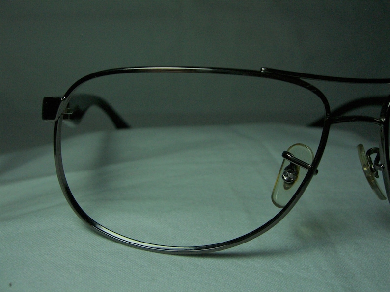 K&ouml;nnte beinhalten: Eine silberne Aviator-Brille mit klaren Gl&auml;sern. Die Brille hat einen d&uuml;nnen Metallrahmen und ist sowohl f&uuml;r M&auml;nner als auch f&uuml;r Frauen geeignet.