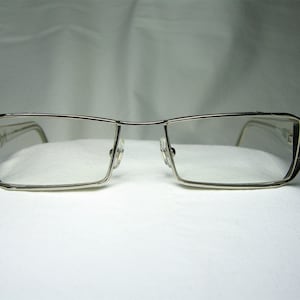 Puede incluir: Gafas rectangulares plateadas con un fino marco de metal.