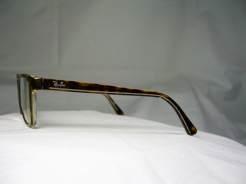 May include: Tortoise shell eyeglasses with a silver Ray-Ban logo on the side.