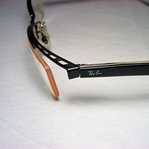May include: Black Ray-Ban eyeglasses with a brown plastic frame and a black metal hinge.