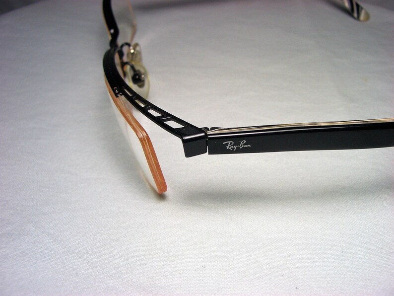 May include: Black Ray-Ban eyeglasses with a brown plastic frame and a black metal hinge.