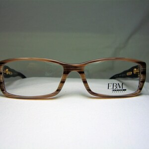 May include: Brown and black striped eyeglasses with gold accents and the text "EBM DESIGN GERMANY" on the right lens.